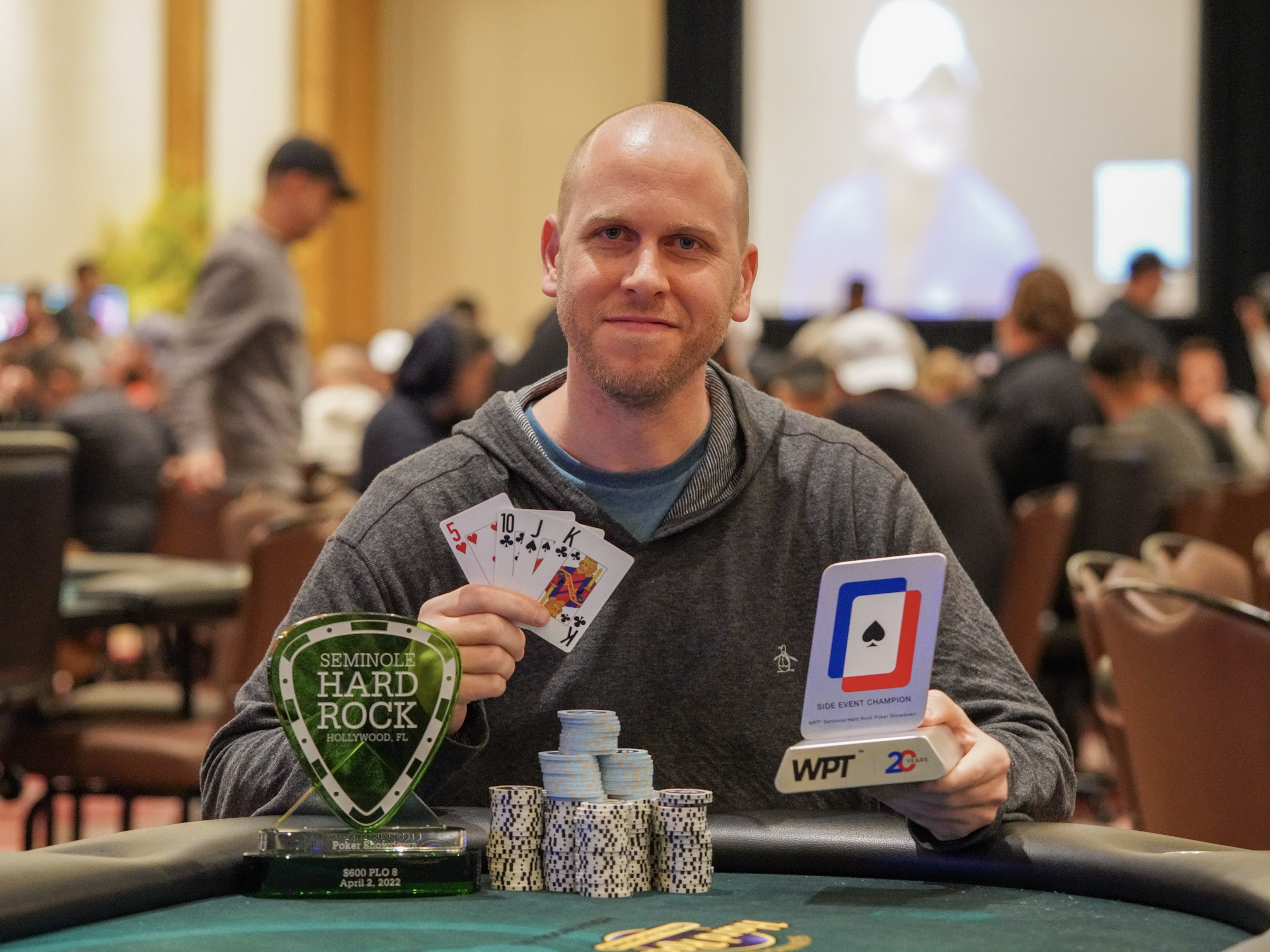 Jeff Madsen holding cards and trophies after his 2022 Seminole Hard Rock Poker Showdown win